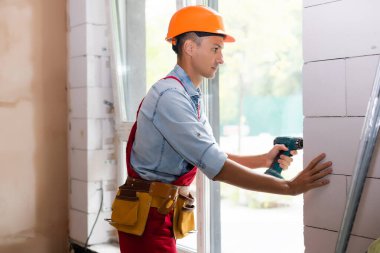 Yenilenmiş bir binanın camına monte eden işçi.