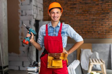 Genç inşaat işçileri baret takıyor.