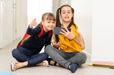 İki küçük liseli kız akıllı telefon ekranına bakıyor.