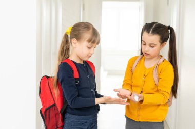 Okula geri dönmek, okul çocukları hijyen, koronavirüs sonrası güvenlik önlemleri. Liseli kız okula gidiyor ve ellerini dezenfektanla yıkıyor.