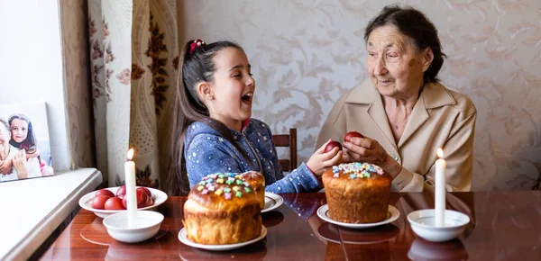 Easter concept. Grandmother with granddaughter are holding Easter eggs at home — Stock Photo, Image