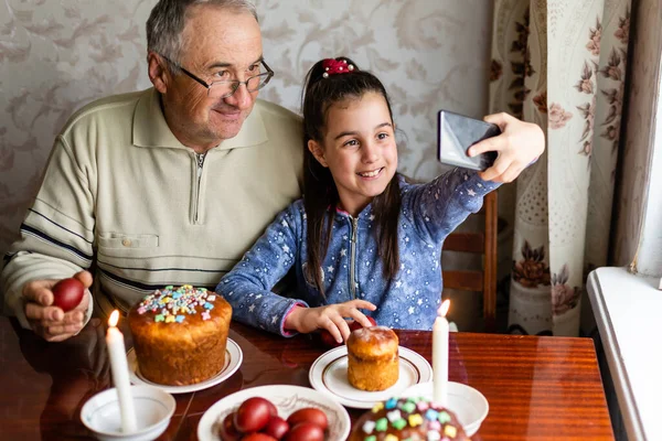 Abuelo y nieta en una mesa festiva para celebrar la Pascua —  Fotos de Stock
