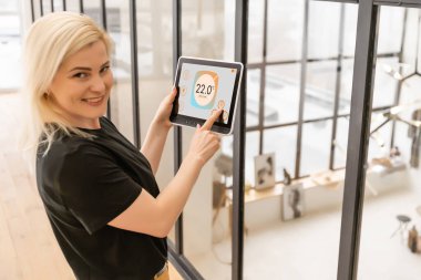 Kadın elleri ekranda akıllı ev sistemi olan bir tablet bilgisayarı tutuyor