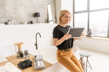 Dijital tablet kullanan gülümseyen genç bir kadın.