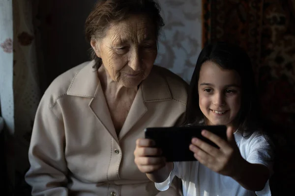 Muito velho bisavó e neta com um smartphone online — Fotografia de Stock