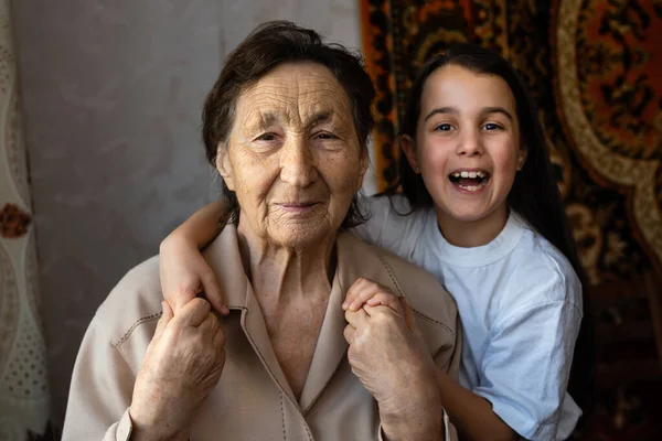 Pequena menina e mulher muito velha. Uma criança a abraçar a avó. Neta. — Fotografia de Stock