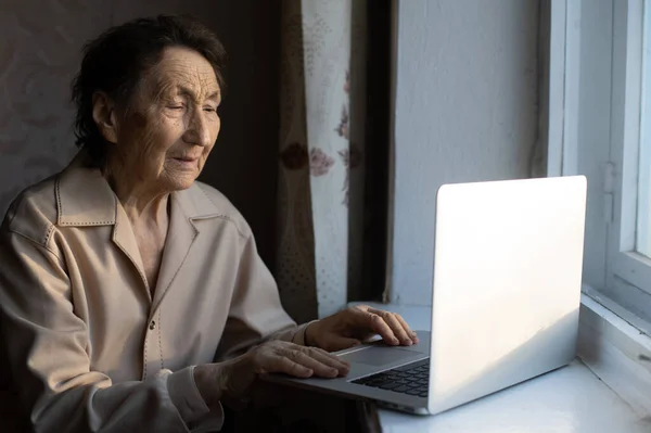 Mulher sênior feliz sentada com sua neta olhando para laptop fazendo chamada de vídeo. Mulher madura conversando com webcam, fazendo chat online em casa durante o auto-isolamento. Tempo de família durante Corona — Fotografia de Stock