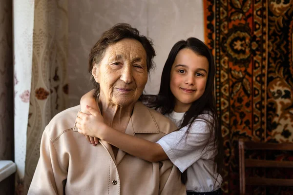 Pequena menina e mulher muito velha. Uma criança a abraçar a avó. Neta. — Fotografia de Stock