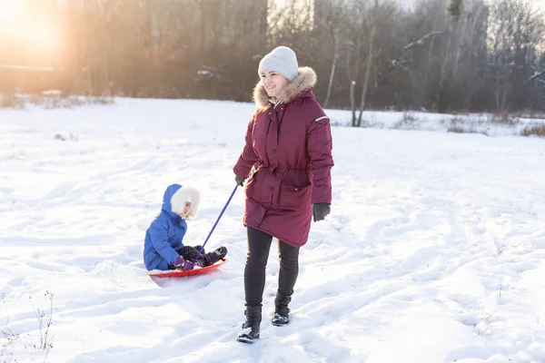 Luge à l'hiver, la mère porte sa fille sur un traîneau sur glace — Photo