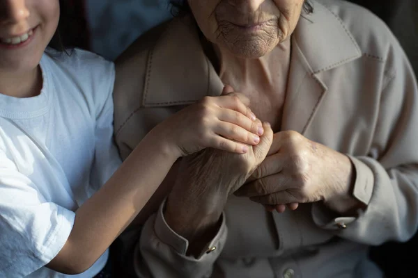 Unrecognizable grandmother and her granddaughter holding hands. — Stock Photo, Image