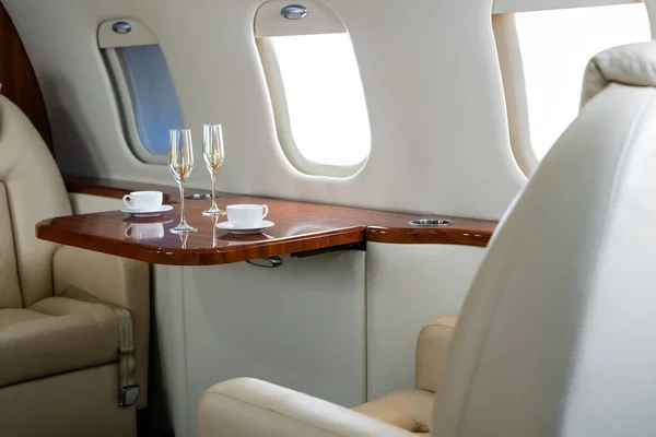 Интерьер бизнес-класса коммерческого пассажирского самолета, кресло и окно, стол и коктейльный бокал с напитком — стоковое фото