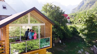 Aile dağ tepe tepe ve güneş üzerinde ahşap kulübe verandada