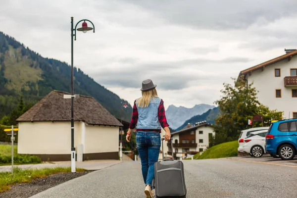 Frau im Sommer macht Urlaub, mit einem Koffer vor dem Hintergrund der Natur und der Berge. Das Konzept des Reisens, Wochenende an einem schönen Ort in den Bergen — Stockfoto