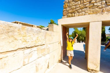 Küçük bir kız Knossos 'taki Minos sarayının duvarlarında resim çekmek için duruyor. Girit, Yunanistan