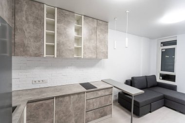 modern compact fitted kitchen with wooden cabinets, stone countertops and built in stove and hob with small appliances on the work surface