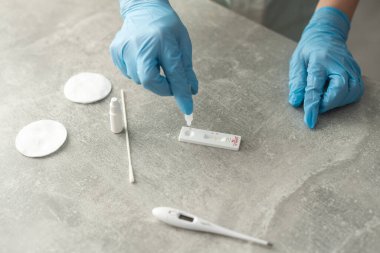 Coronavirus SARS-CoV-2, Covid-19 için antikorlar için COVID-19 testi yapın. Sıhhiyeciler eldiven ile kan testi uygular. Hasta parmaklar, mavi nane arkaplanı