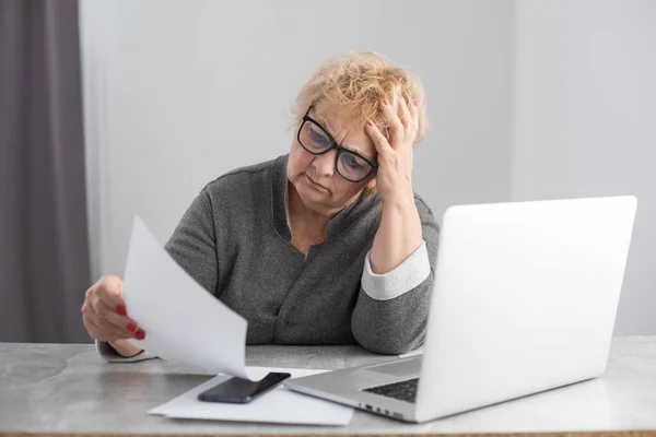 Oudere vrouw van middelbare leeftijd huisvrouw lezen papieren brief of factuur zittend in de keuken op kantoor, het controleren van de financiële belastingen vergoedingen, het bekijken van bankrekening lening tarieven informatie, medische verzekering kosten — Stockfoto