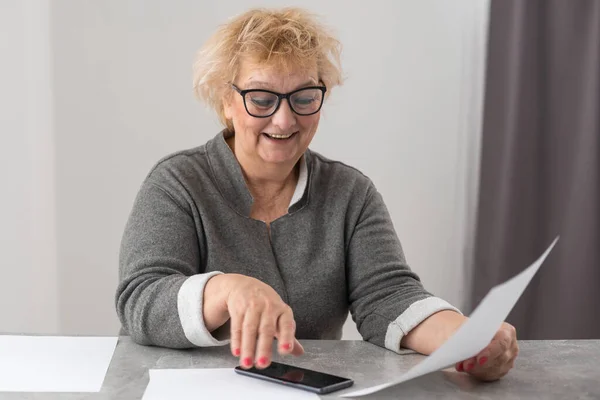 Eine ältere Frau füllt eine Quittung für die Bezahlung von Versorgungsrechnungen aus. — Stockfoto