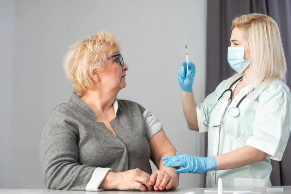 Ιατρός που εμβολιάζει ηλικιωμένο ασθενή στην κλινική με χώρο αντιγραφής. Γιατρός κάνει ένεση σε ηλικιωμένη γυναίκα στο νοσοκομείο. Νοσοκόμα που κρατάει σύριγγα πριν κάνει το εμβόλιο του Covid- 19 ή του Coronavirus. — Φωτογραφία Αρχείου