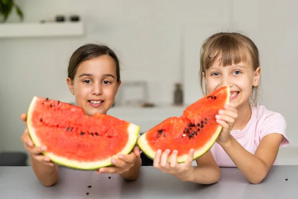 Dois miúdos a comer uma fatia de melancia. As crianças comem fruta ao ar livre. Lanche saudável para crianças. — Fotografia de Stock