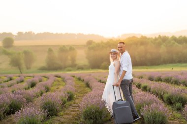 Lavanta tarlasında bavulu olan kadın ve erkek.,