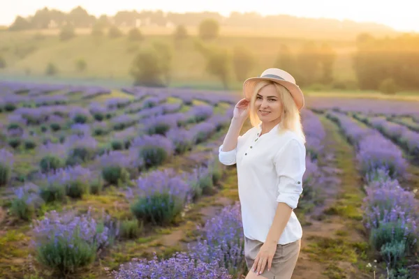 若いブロンドの女性旅行者はラベンダーの花で囲まれたラベンダー畑でわら帽子をかぶって. — ストック写真