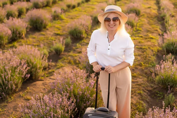 Frau mit Koffer in der Hand in einem Lavendelfeld am Sommernachmittag — Stockfoto