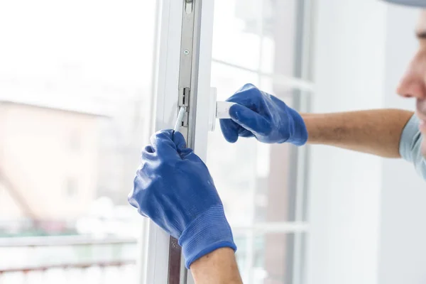 Un trabajador con guantes comprueba la cerradura de una nueva puerta de plástico —  Fotos de Stock