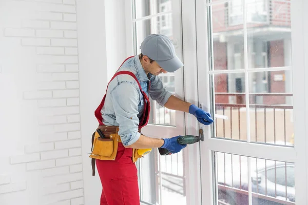 Manlig fixering lås till fönster med elektrisk skruvmejsel — Stockfoto
