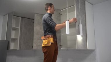Professional electrician twisting bulb installing light in apartment, service.