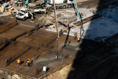 Bir sürü inşaat malzemesi, inşaat halindeki evler, vinçler ve işçiler olan büyük bir inşaat alanı. Hidrolik çekiçle yere çakılan kümeler. Metro inşaat projesi