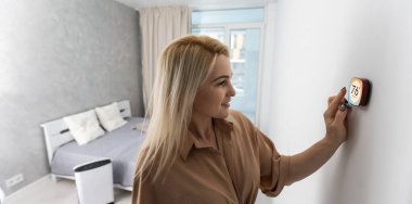 Akıllı ev sistemini kullanan ya da evden çıkmadan önce modern alarm sistemini çalıştıran hoş bir kadın. Mutlu kadın eve ya da daireye döndüğünde kolay güvenlik teknolojisini kapatıyor..