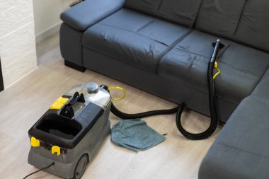 Evdeki elektrikli süpürgeyle kanepeyi temizleyen kadına yakın çekim