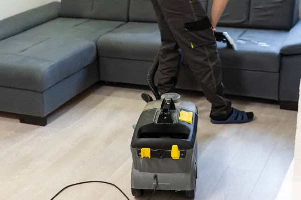 Man stomerij werknemer schoonmaken sofa met professioneel extractie methode — Stockfoto