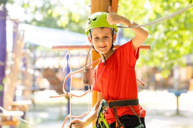 Güzel bir okul çocuğu macera parkında güneşli bir günün tadını çıkarıyor.