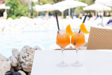 Parlak turuncu kokteyl havuzun kenarında duruyor.