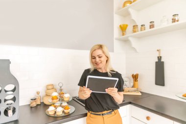 Dijital tablet kullanan gülümseyen genç bir kadın.