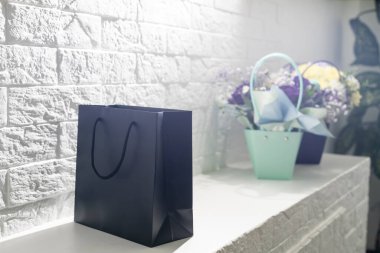 Beyaz arka planda buket ve siyah hediye çantası.