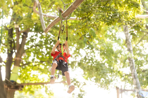 Bonito menino da escola desfrutando de um dia ensolarado em um parque de atividades de aventura de escalada — Fotografia de Stock