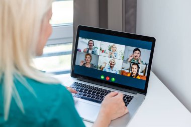 Evde video konferansı için dizüstü bilgisayar kullanan genç bir kadının kırpılmış görüntüsü