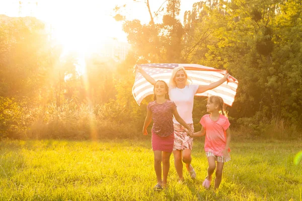 Happy family with the American flag in a wheat field at sunset. Independence Day, 4th of July. — Stock Photo, Image