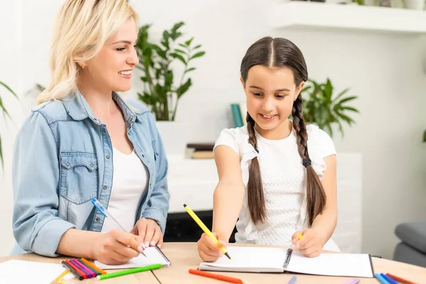 Skola flicka och mor tillsammans gör läxor i hemmet — Stockfoto