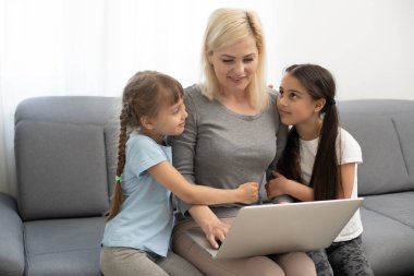 Çocukla birlikte ev ofisinden çalışıyoruz. Mutlu anne-kız çevrimiçi alışveriş yapıyor, birlikte dizüstü bilgisayar kullanıyorlar. Kadın kucaklayan çocuk. Mutfak masasında serbest çalışan bir işyeri. Kadın işi, sanal iletişim..