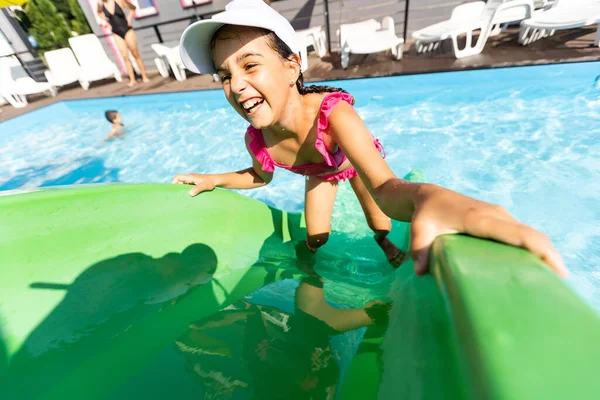 Simning - liten flicka leker i blått vatten — Stockfoto