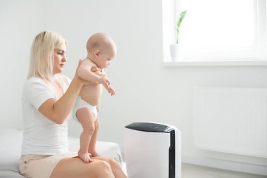 Anne ve bebek evde hava temizleyicinin yanında.
