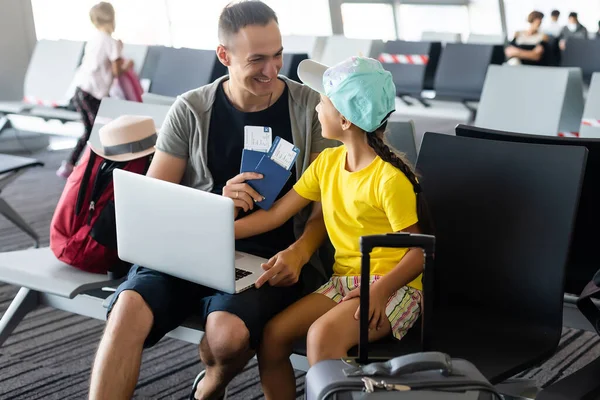 Guapo joven padre y su hija pequeña usando el ordenador portátil en el aeropuerto —  Fotos de Stock