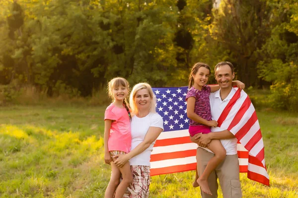 Happy family in field with USA, american flag on back. — Stock Photo, Image