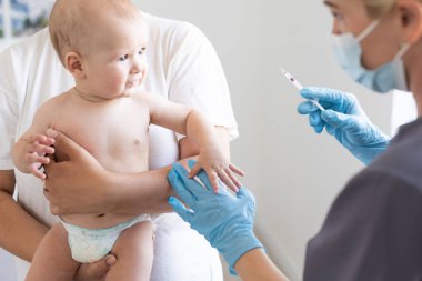 Çocuk doktoru küçük çocuğa aşı yapıyor.