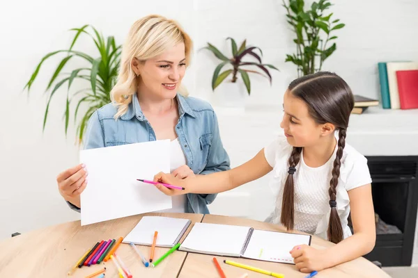 Mooi school meisje doen huiswerk met moeder thuis — Stockfoto