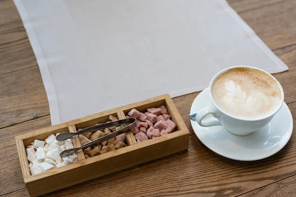 Kaffekopp och olika typer av kaffe och socker på ett träbord — Stockfoto